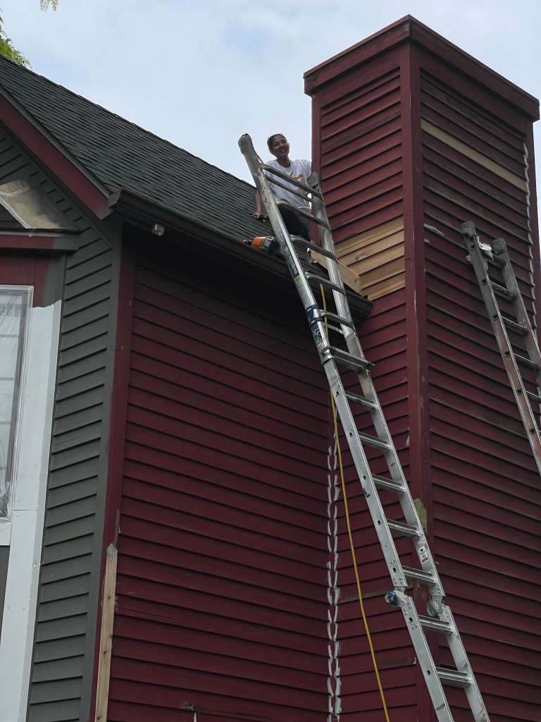Team on ladder painting dark red home